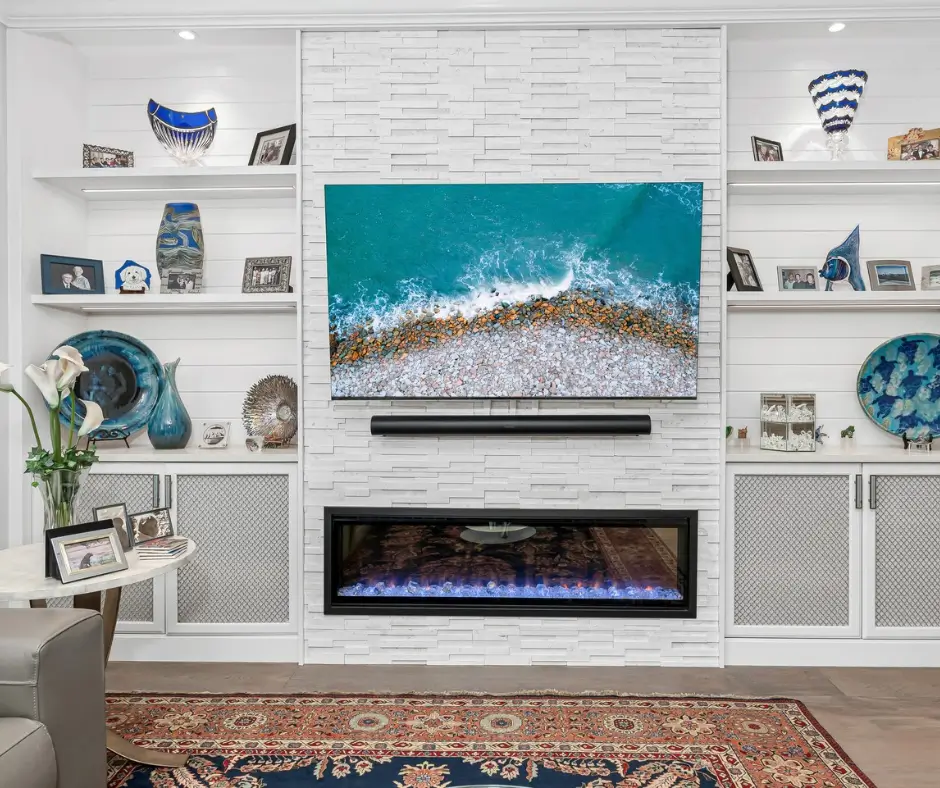 Cozy stone fireplace wall with mounted TV and rustic wooden mantel.